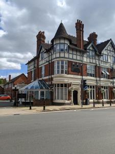 un grand bâtiment en briques au coin d'une rue dans l'établissement Plough Hotel, à Northampton