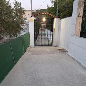 uma entrada para um portão com uma cerca verde em Ξενώνας Vasiliki em Vathí