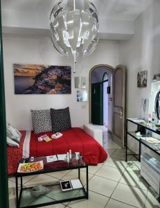 a bedroom with a red bed and a large chandelier at YourHome - La Dimora Di Nonna Angela in Positano