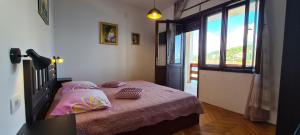 Schlafzimmer mit einem Bett mit rosa Bettwäsche und einem Fenster in der Unterkunft Apartment Next to the sea in Jelsa