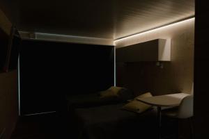 um quarto escuro com uma cama e uma mesa em Hotel OmaBox - Nivala - Oma huoneisto saunalla em Nivala