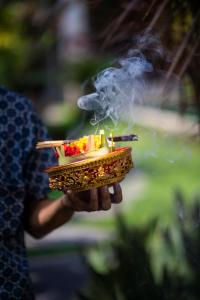 a person holding up a tray of smoke at Lili Cottage Ubud in Ubud