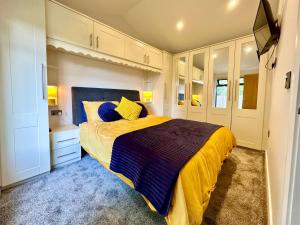 a bedroom with a bed with a yellow and blue blanket at The Birches with Hot Tub in York +27 photos