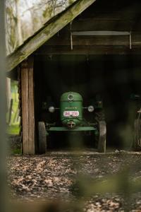 a green truck sitting inside of a shed at Hoeve de Reetjens - La Porcherie in Bilzen