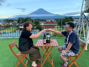 dos hombres sentados en una mesa con una botella de vino en Akaishi Ryokan en Fujikawaguchiko