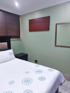 1 dormitorio con 1 cama blanca grande con una foto en la pared en The Sails en Durban