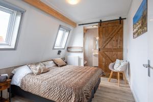 1 dormitorio con cama y puerta corredera de granero en Wulpenweid Bed & Parking, en Den Burg