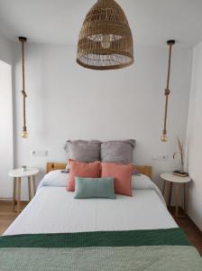 1 dormitorio con 1 cama con almohadas rosas y grises en Apartamentos La Casa del Maestro en Alhama de Aragón
