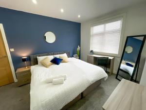 a bedroom with a large white bed with a blue wall at 12min to City - FREE Parking - Christie NHS - Contractor Friendly - IRWELL STAYS in Manchester