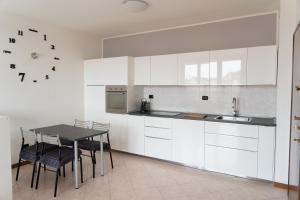 uma cozinha com armários brancos e uma mesa com cadeiras em Parcheggio Privato - Appartamento a Milano em Corsico