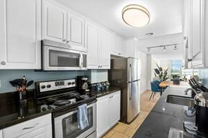 una cocina con armarios blancos y electrodomésticos de acero inoxidable en Sunset Haven 3-Bedrooms 2-Baths, en Los Ángeles