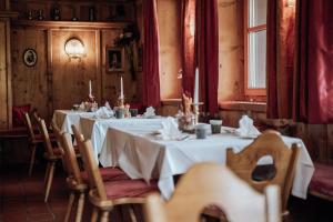 une salle à manger avec des tables et des chaises blanches ainsi qu'une fenêtre dans l'établissement Hotel Goldener Berg, à Lech am Arlberg