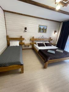 a bedroom with two beds and a bench in it at Zarichna Lyks in Slavske