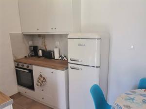 a kitchen with a white refrigerator and a stove at Blue central apt 10 min to the port/ wash machine in Lávrion