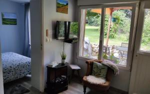 Pokój z krzesłem i telewizorem oraz sypialnią w obiekcie Petit cottage w mieście Saint-Pierre-la-Garenne