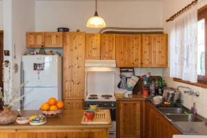 cocina con armarios de madera y nevera blanca en LESKA APARTMENT IN ARGYROUPOLI, en Argyroupolis