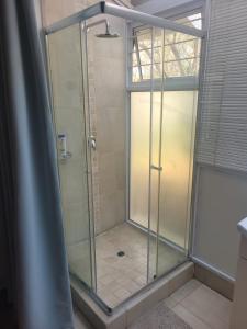 una ducha con puerta de cristal en un baño en Eden Guesthouse, en Johannesburgo