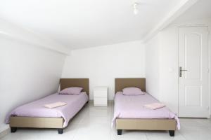 勒布朗－梅尼爾的住宿－Le blanc 23D 1ère ETG F2 duplex face gauche，配有白色墙壁和紫色床单的客房内的两张床
