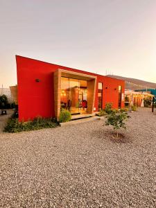 um edifício vermelho num estaleiro de gravilha com um edifício em Desert Lodges - La Terracota em Ica