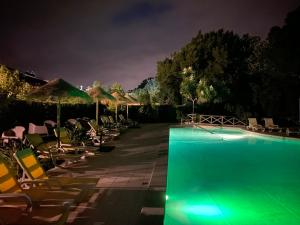 uma piscina à noite com cadeiras e guarda-sóis em Charm Azenha DÓbidos Farm em Olho Marinho
