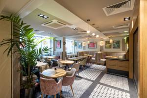 ロンドンにあるポイント A ホテル ロンドン キングス クロス セント パンクラスのテーブルと椅子、植物のあるレストラン