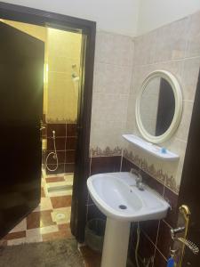 ein Bad mit einem Waschbecken und einem Spiegel in der Unterkunft الراحة بلازا للشقق المفروشة in Sharorah