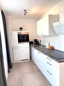 eine Küche mit weißen Schränken und einer schwarzen Arbeitsplatte in der Unterkunft Leon Art Apartment in Leipzig