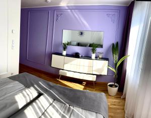 ein Schlafzimmer mit einer lila Wand und einem Spiegel in der Unterkunft Leon Art Apartment in Leipzig
