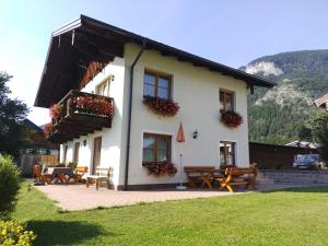 a white house with tables and benches in a yard at Berningerhof in St. Wolfgang