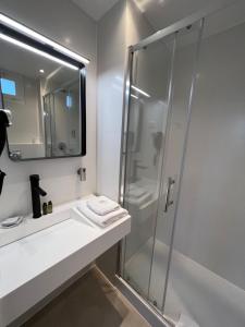 a bathroom with a glass shower and a sink at Paris Saint Cloud Hôtel in Saint-Cloud
