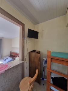 Dormitorio con cama, escritorio y TV en Kitnets da Tia Zeni, en Arraial do Cabo