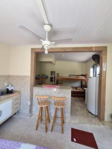 a kitchen with two bar stools and a refrigerator at Kitnets da Tia Zeni in Arraial do Cabo