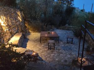 a wooden table and benches in a stone yard at night at Casa de campo Fuencaliente, entorno natural, chimenea, piscina in Cañete la Real