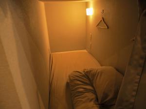 ein kleines Zimmer mit einem Bett und einer Lampe in der Unterkunft bnb+ Secret Base Mejiro in Tokio