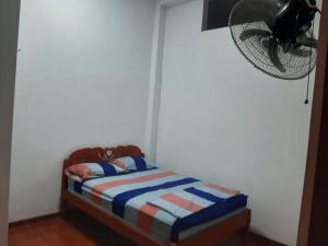 Cama pequeña en habitación con ventilador en Alojamiento Casa Grande en Iquitos