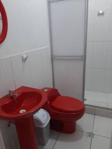 baño con aseo rojo y lavabo rojo en Alojamiento Casa Grande en Iquitos