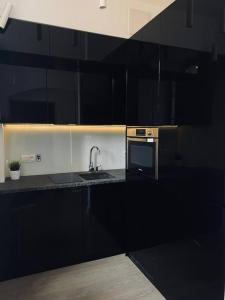a black kitchen with a sink and a microwave at Lux apartment near Wawel in Krakow