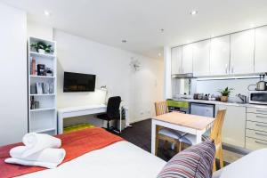ein Schlafzimmer mit einem Bett und einem Schreibtisch sowie eine Küche in der Unterkunft Simple on Swanston - A Central Student Accom Studio in Melbourne