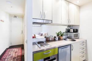 eine Küche mit weißen Schränken und einem Herd mit Backofen in der Unterkunft Simple on Swanston - A Central Student Accom Studio in Melbourne + 1 Foto