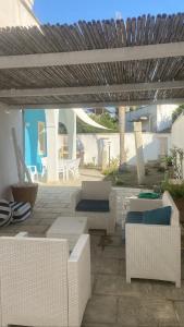 een patio met witte meubels en een houten pergola bij La Casa Turchina a 3 km da Otranto in Giurdignano