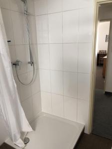 a bathroom with a shower with a white tile wall at Ferienwohnung Innenstadt in Marktbreit