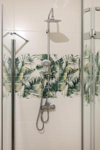 a shower in a bathroom with a tropical wallpaper at Apartament Flora - apartament blisko morza in Gdańsk