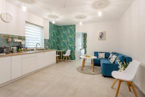 a kitchen and a living room with a blue couch at Apartament Flora - apartament blisko morza in Gdańsk