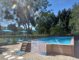 a swimming pool with a table and chairs and an umbrella at Mobil-Home 1à 4 Personnes in Attigny