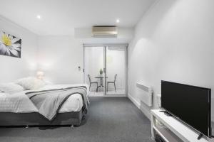 sypialnia z łóżkiem i telewizorem z płaskim ekranem w obiekcie Backpacker's Delight on Lygon Street near RMIT w Melbourne