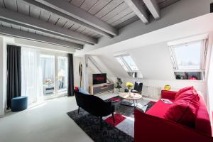 Luxury 4-rooms apartment with terrace في براغ: غرفة معيشة مع أريكة حمراء وكراسي