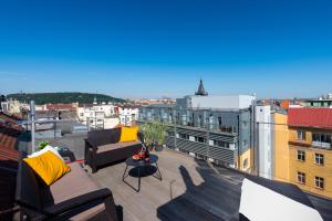 Luxury 4-rooms apartment with terrace في براغ: بلكونه مع الاثاث واطلاله على مدينه
