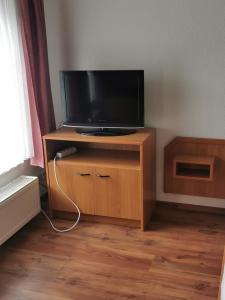 a television on a wooden stand in a room at Pension zum Park in Goldberg