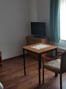 a living room with a table and a tv at Pension zum Park in Goldberg
