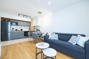 a living room with a blue couch and a kitchen at Alpha Level Apartment in Zadar